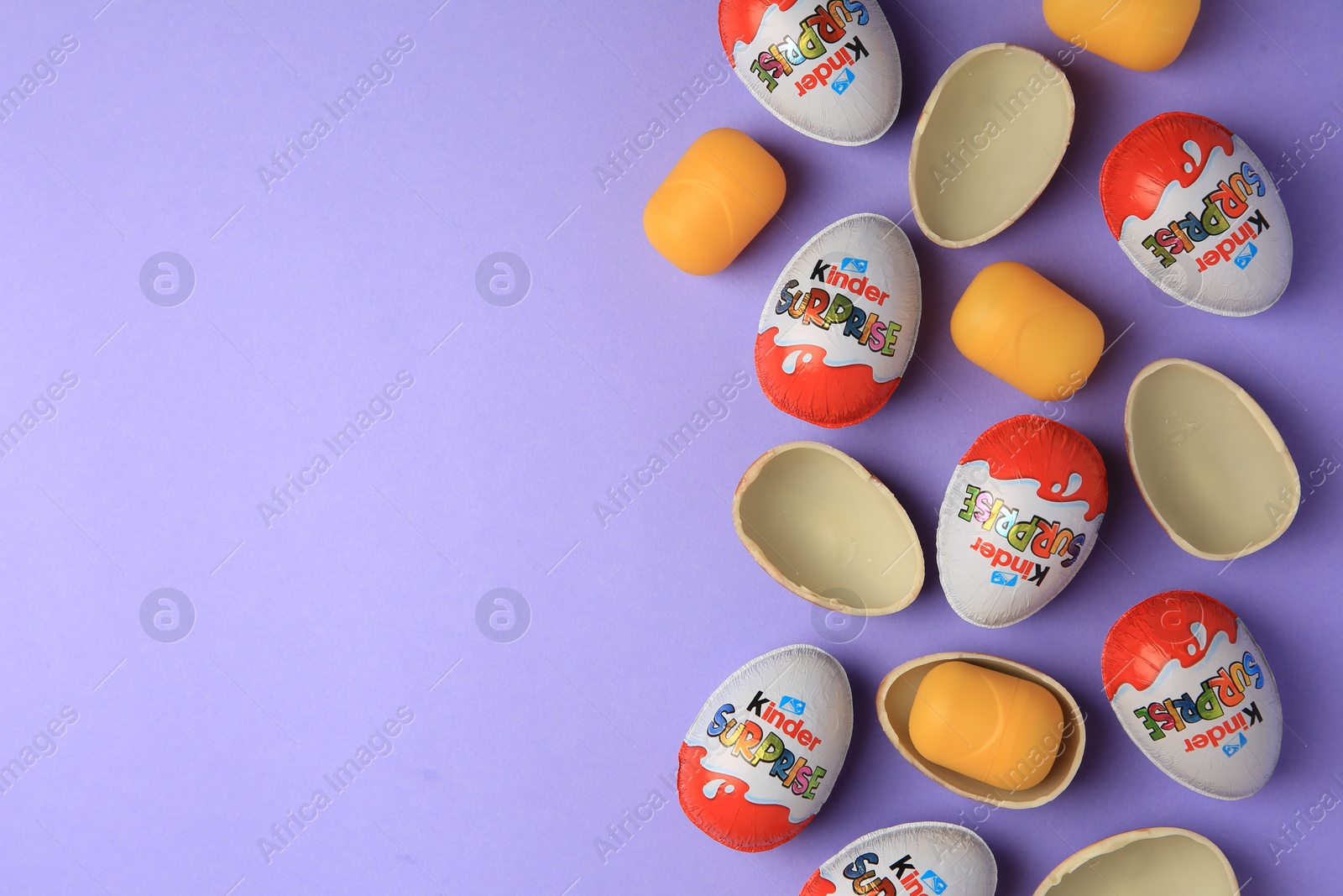 Photo of Sveti Vlas, Bulgaria - June 29, 2023: Kinder Surprise Eggs and plastic capsules on violet background, flat lay. Space for text