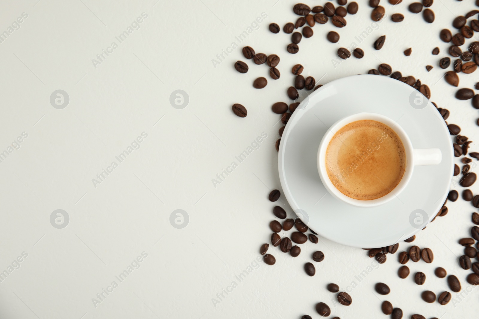 Photo of Cup of hot aromatic espresso and roasted beans on white table, flat lay. Space for text