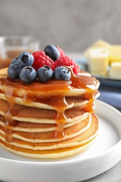 Photo of Delicious pancakes with fresh berries and syrup on table, closeup