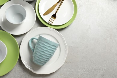 Beautiful ceramic dishware, cup and cutlery on light grey table, flat lay. Space for text