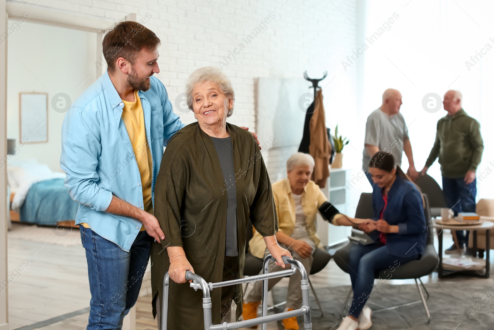 Photo of Care worker helping to elderly woman with walker in geriatric hospice