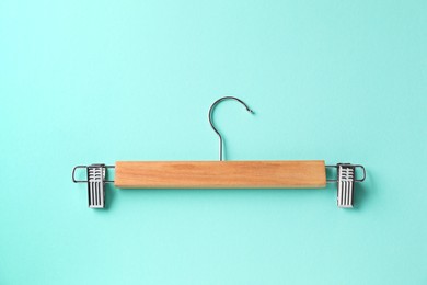 Photo of Wooden hanger with clips on light blue background, top view