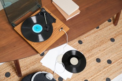 Stylish turntable with vinyl discs and headphones in room, about view