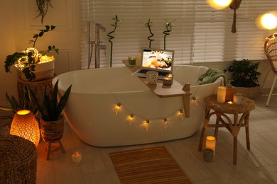 Photo of Stylish bathroom interior with green houseplants and string lights. Idea for design