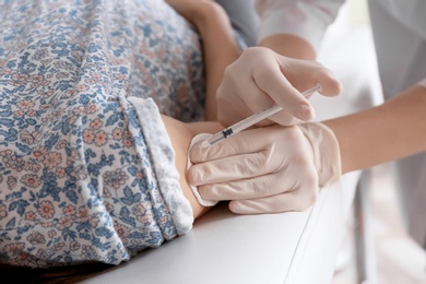 Photo of Doctor vaccinating female patient in clinic, closeup