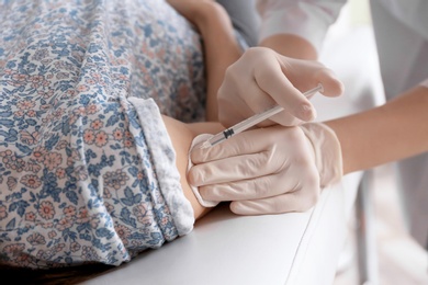 Doctor vaccinating female patient in clinic, closeup