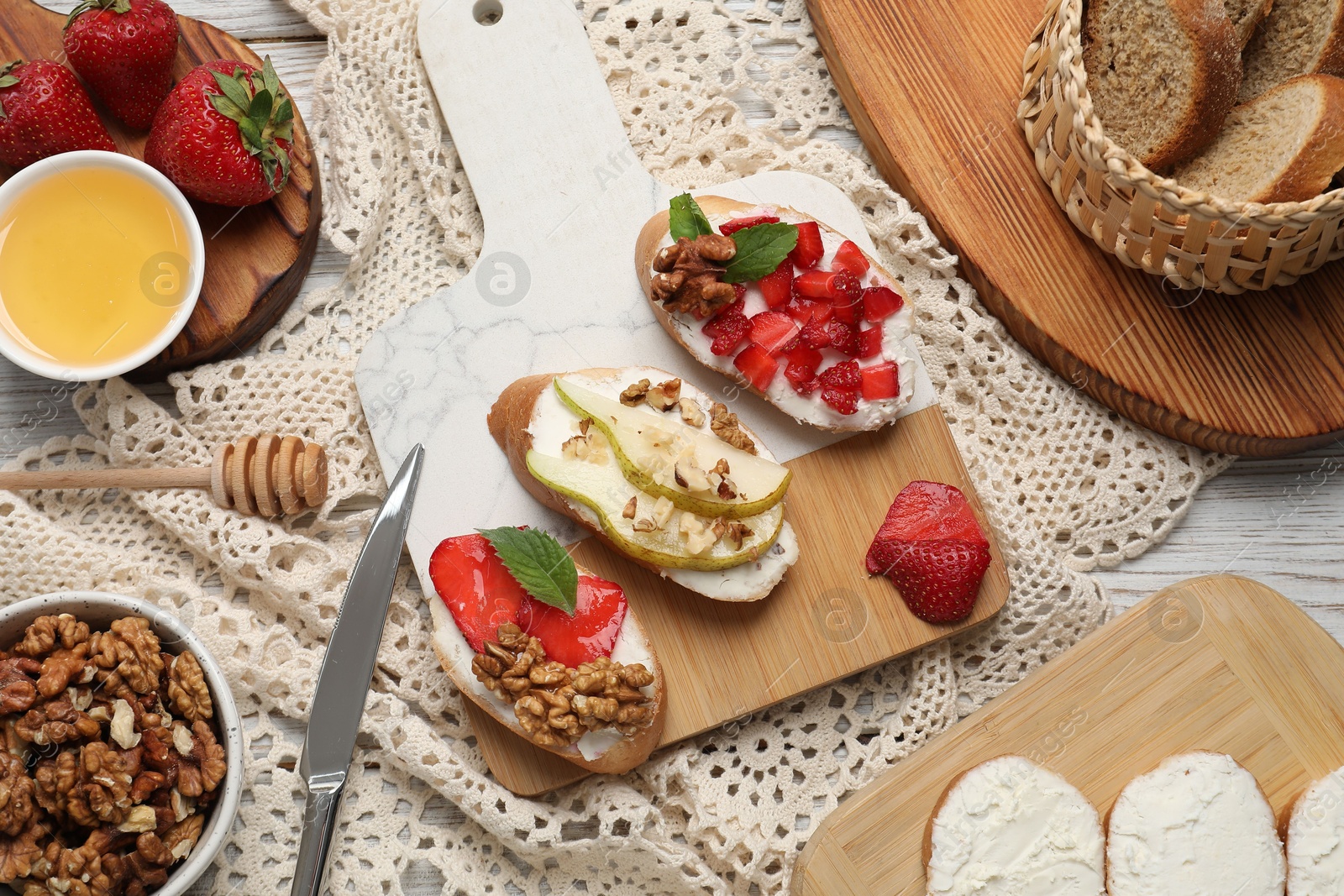 Photo of Board with different tasty ricotta bruschettas and ingredients on table, flat lay