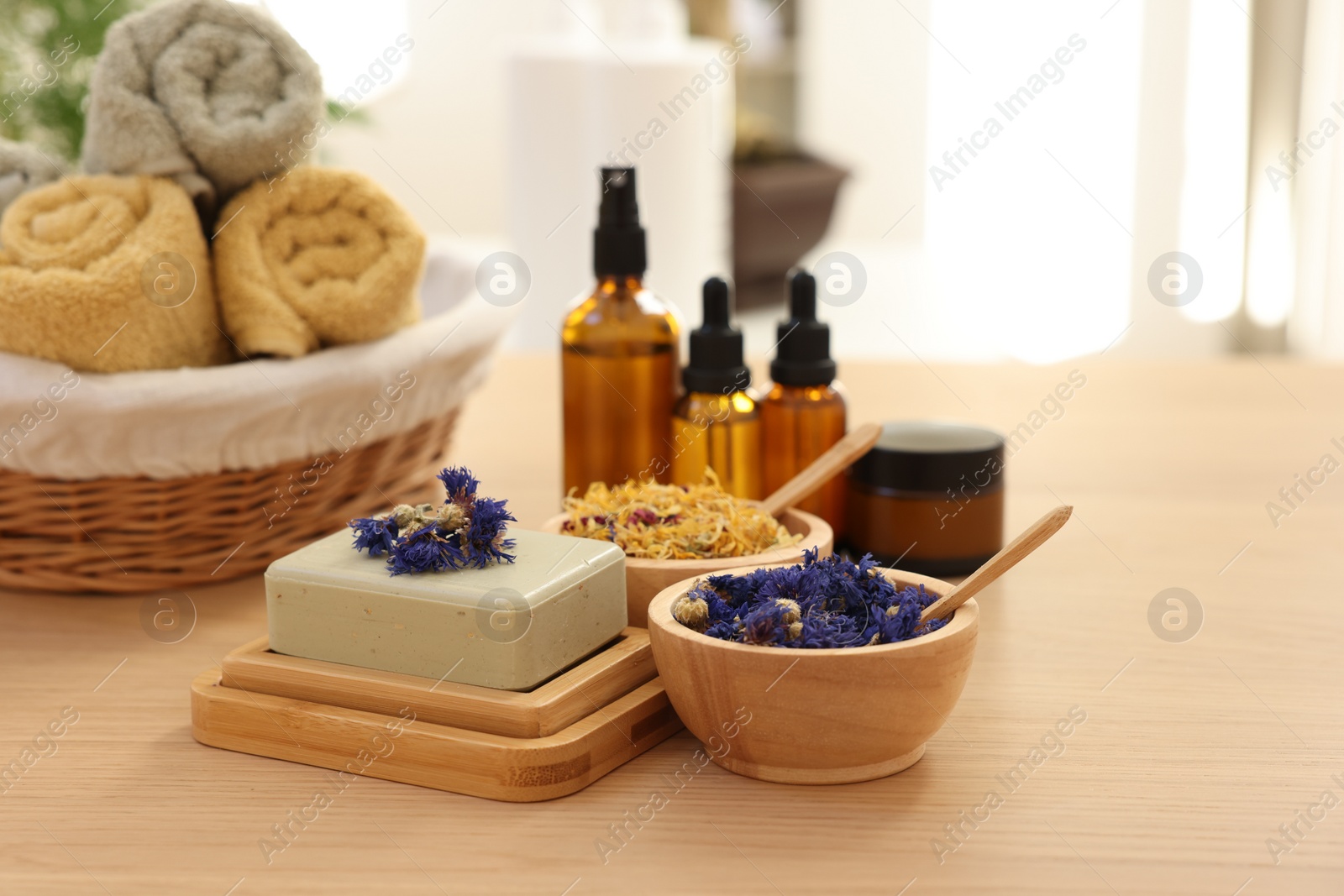 Photo of Soap bar, dry flowers, bottles of essential oils, jar with cream and towels on wooden table indoors. Spa time