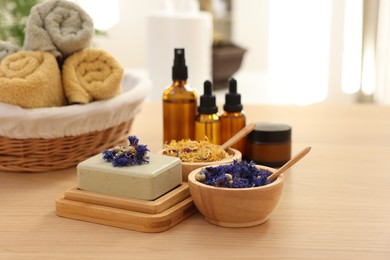 Photo of Soap bar, dry flowers, bottles of essential oils, jar with cream and towels on wooden table indoors. Spa time