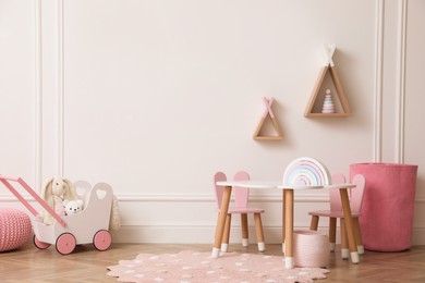 Photo of Cute child room interior with furniture, toys and wigwam shaped shelves on white wall