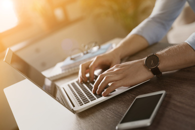 Image of Man working with laptop at wooden table indoors, closeup