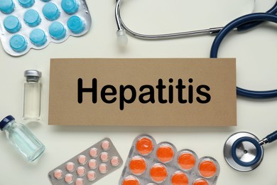 Photo of Cardboard with word Hepatitis and medical supplies on beige background, flat lay