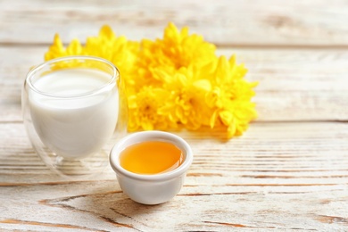 Photo of Glass of milk and bowl with honey on wooden background