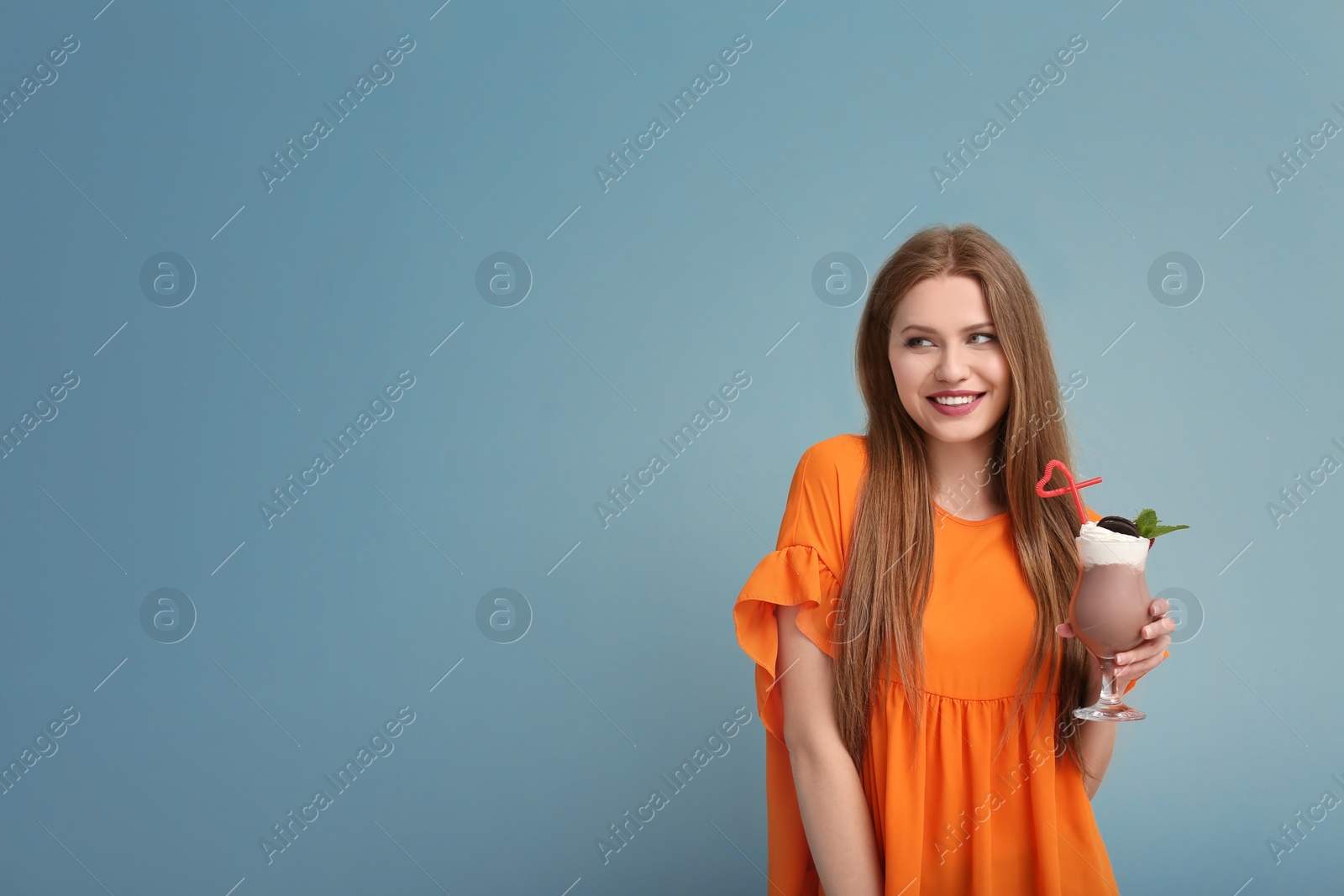 Photo of Young woman with glass of delicious milk shake on color background