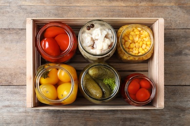 Jars with pickled vegetables on wooden table, top view
