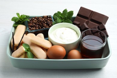 Photo of Baking dish with ingredients for tiramisu on white wooden table