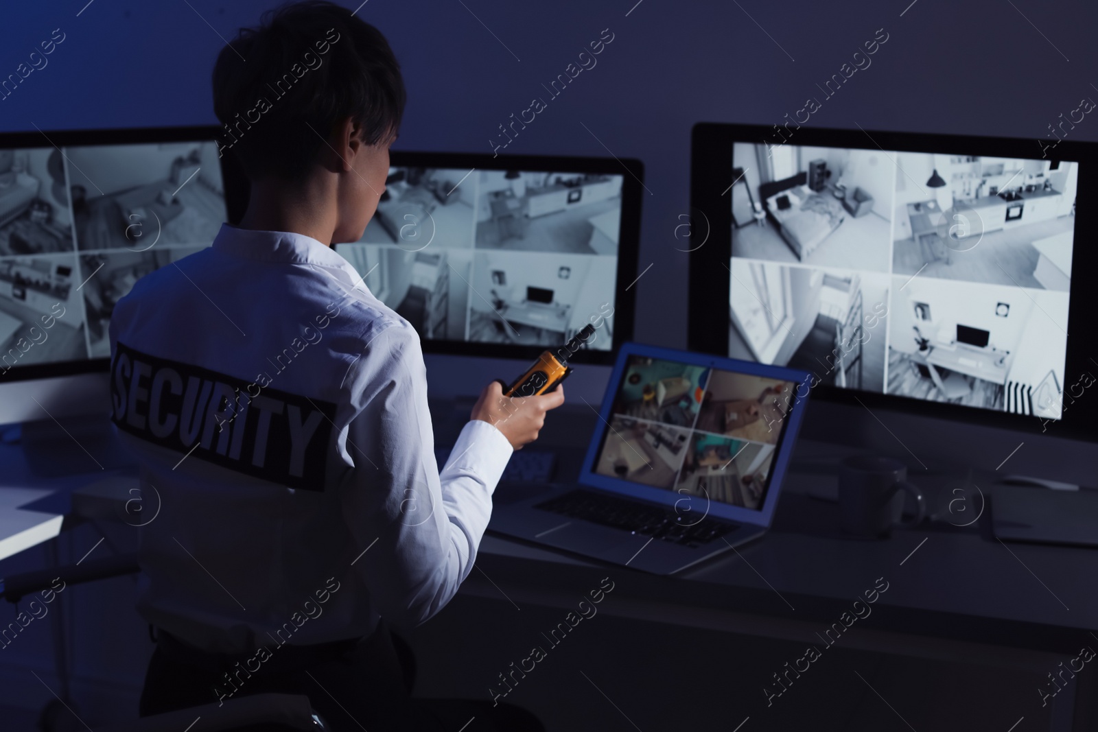 Photo of Female security guard with portable transmitter monitoring home cameras indoors at night