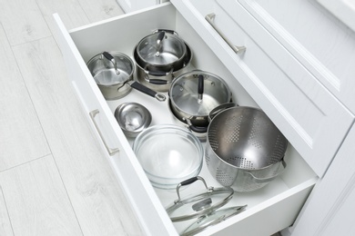 Open drawer with pots and pan indoors. Order in kitchen