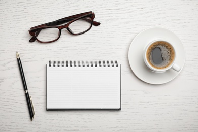 Flat lay composition with notebook and cup of aromatic coffee on wooden background