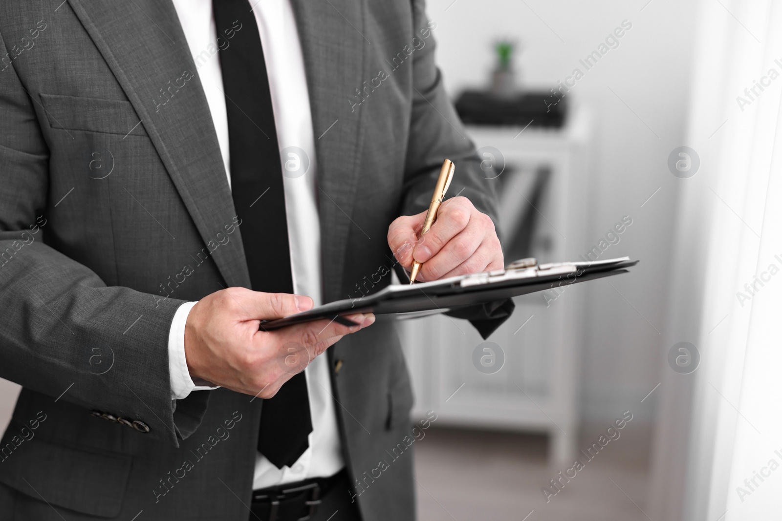 Photo of Notary writing notes in clipboard with pen indoors, closeup. Space for text