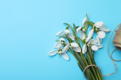 Photo of Beautiful snowdrops and twine on light blue background, flat lay. Space for text