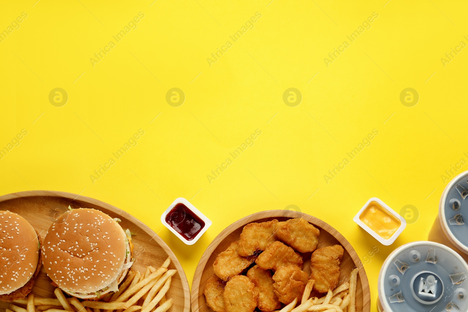 Photo of Different fast food on yellow background, flat lay. Space for text