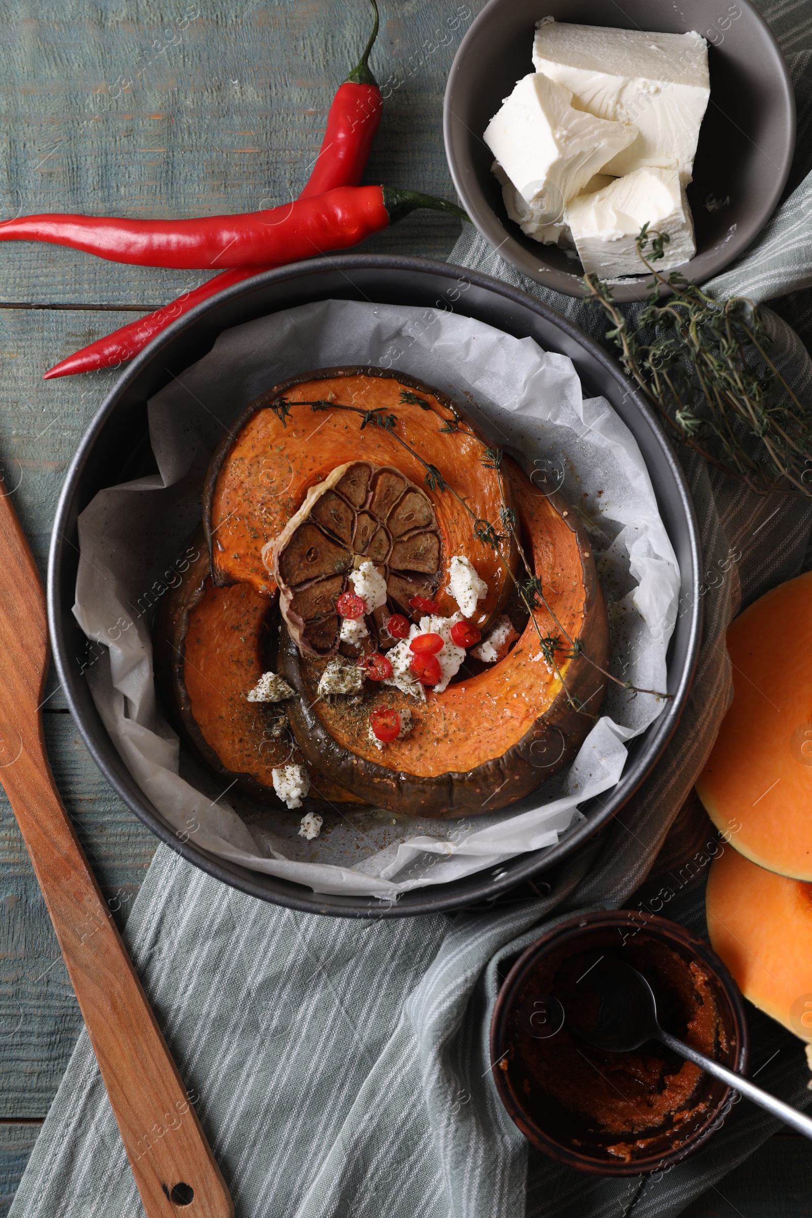 Photo of Freshly baked pumpkin slices with cheese, garlic, chili pepper and thyme on grey wooden table, flat lay