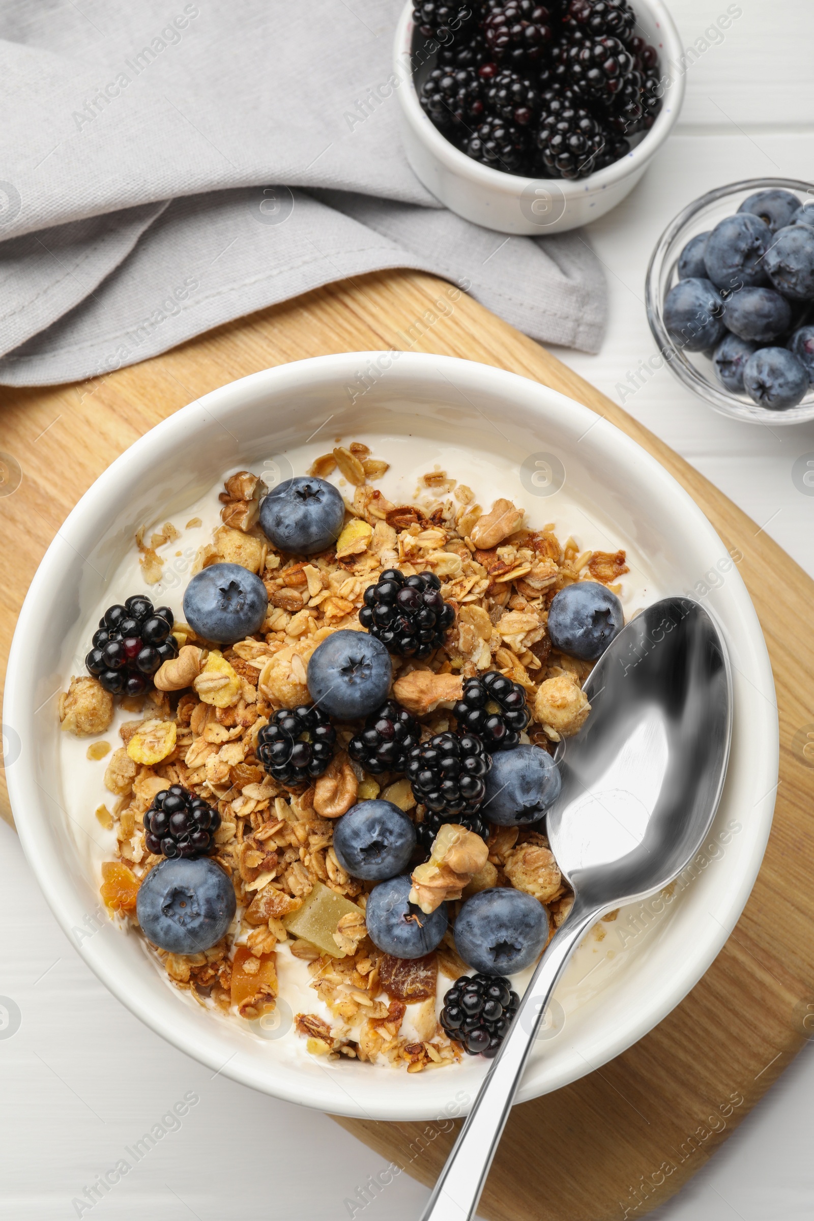 Photo of Bowl of healthy muesli served with berries on white wooden table, flat lay