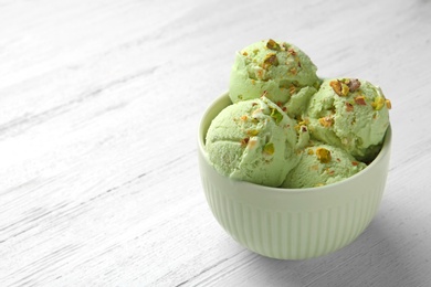 Photo of Tasty pistachio ice cream on white wooden table, space for text