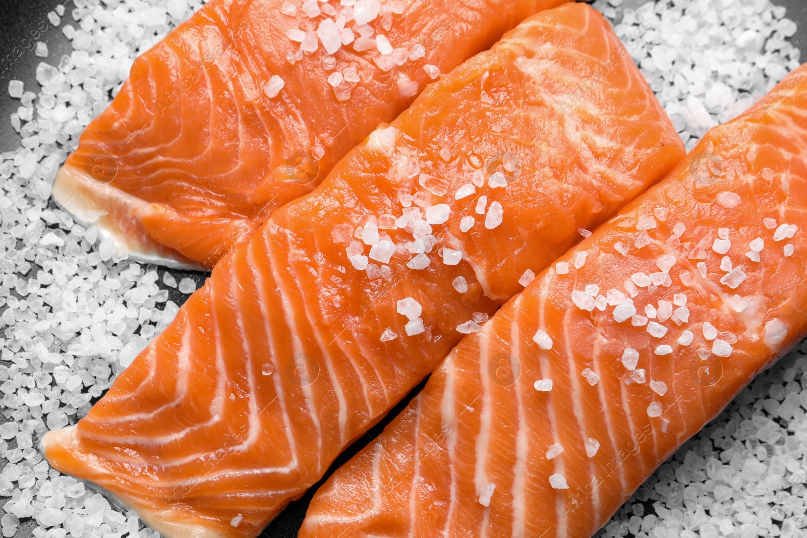 Photo of Fresh raw salmon with salt on black background, flat lay