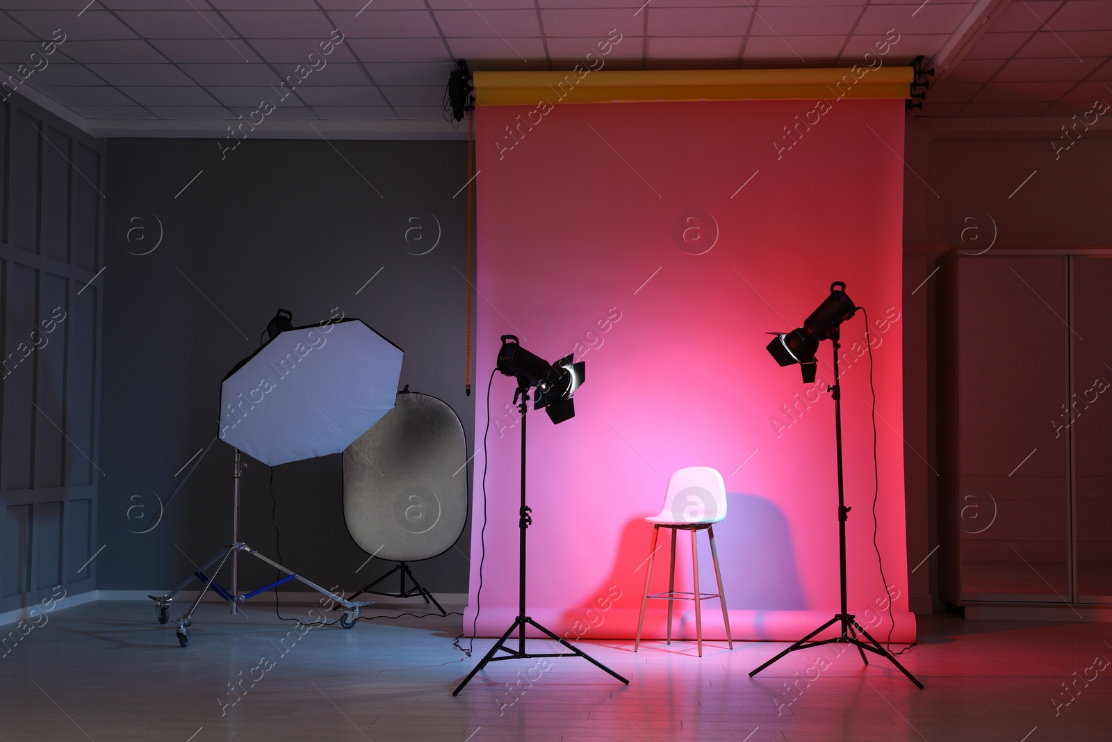 Photo of Photo background in neon lights and professional lighting equipment inside modern studio