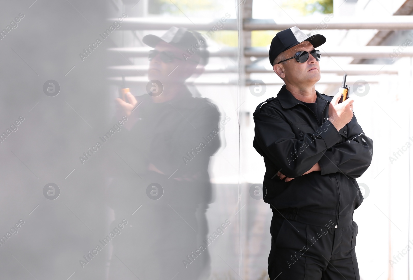 Photo of Male security guard using portable radio transmitter outdoors