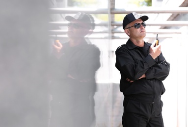 Male security guard using portable radio transmitter outdoors