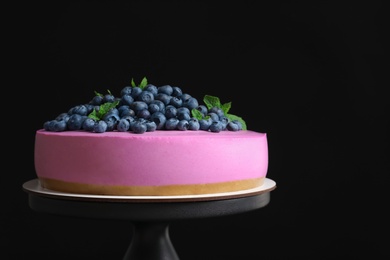 Stand with tasty blueberry cake on black background. Space for text