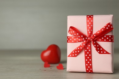 Beautiful gift box with red hearts on wooden table. Space for text