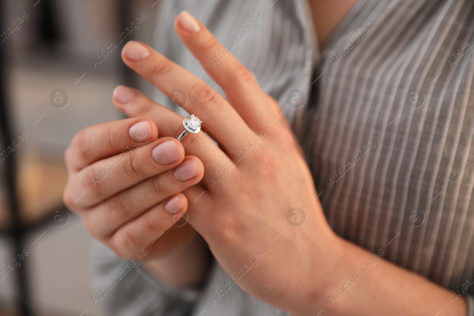 Photo of Woman taking off wedding ring indoors, closeup. Divorce concept