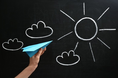 Photo of Woman holding paper plane near blackboard, closeup