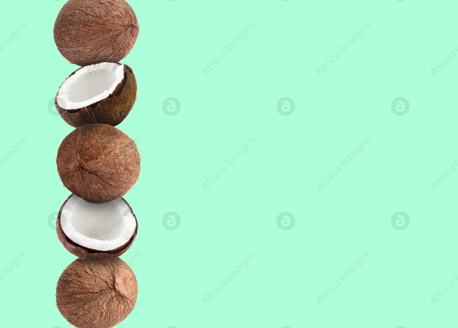 Image of Stack of fresh coconuts on pale light turquoise background. Space for text