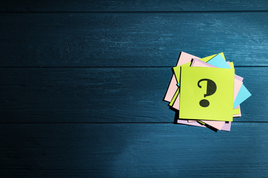 Paper cards with question mark on blue wooden background, top view. Space for text