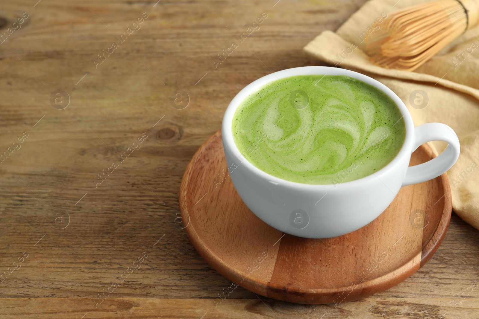 Photo of Cup of aromatic matcha latte on wooden table. Space for text