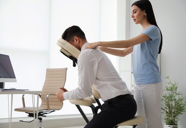 Photo of Man receiving massage in modern chair indoors