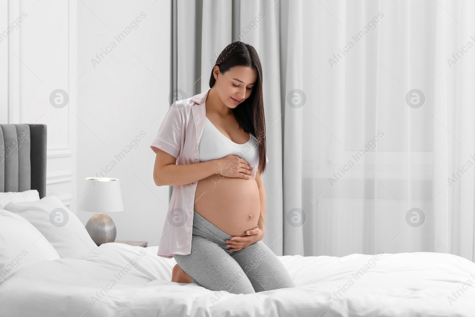 Photo of Beautiful pregnant woman on bed at home