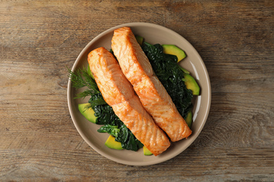 Photo of Tasty salmon with spinach and avocado on wooden table, top view