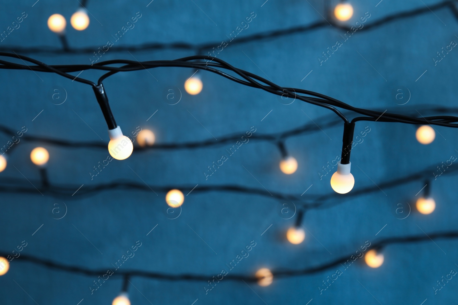 Photo of Beautiful Christmas lights on color background, closeup