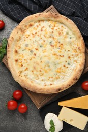 Photo of Delicious cheese pizza and ingredients on dark grey table, flat lay