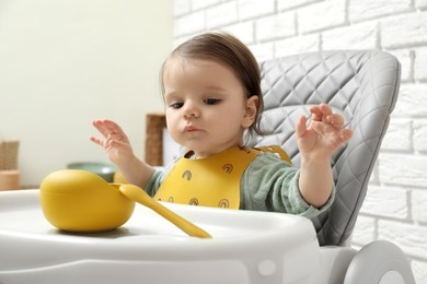 Photo of Cute little baby sitting in high chair indoors