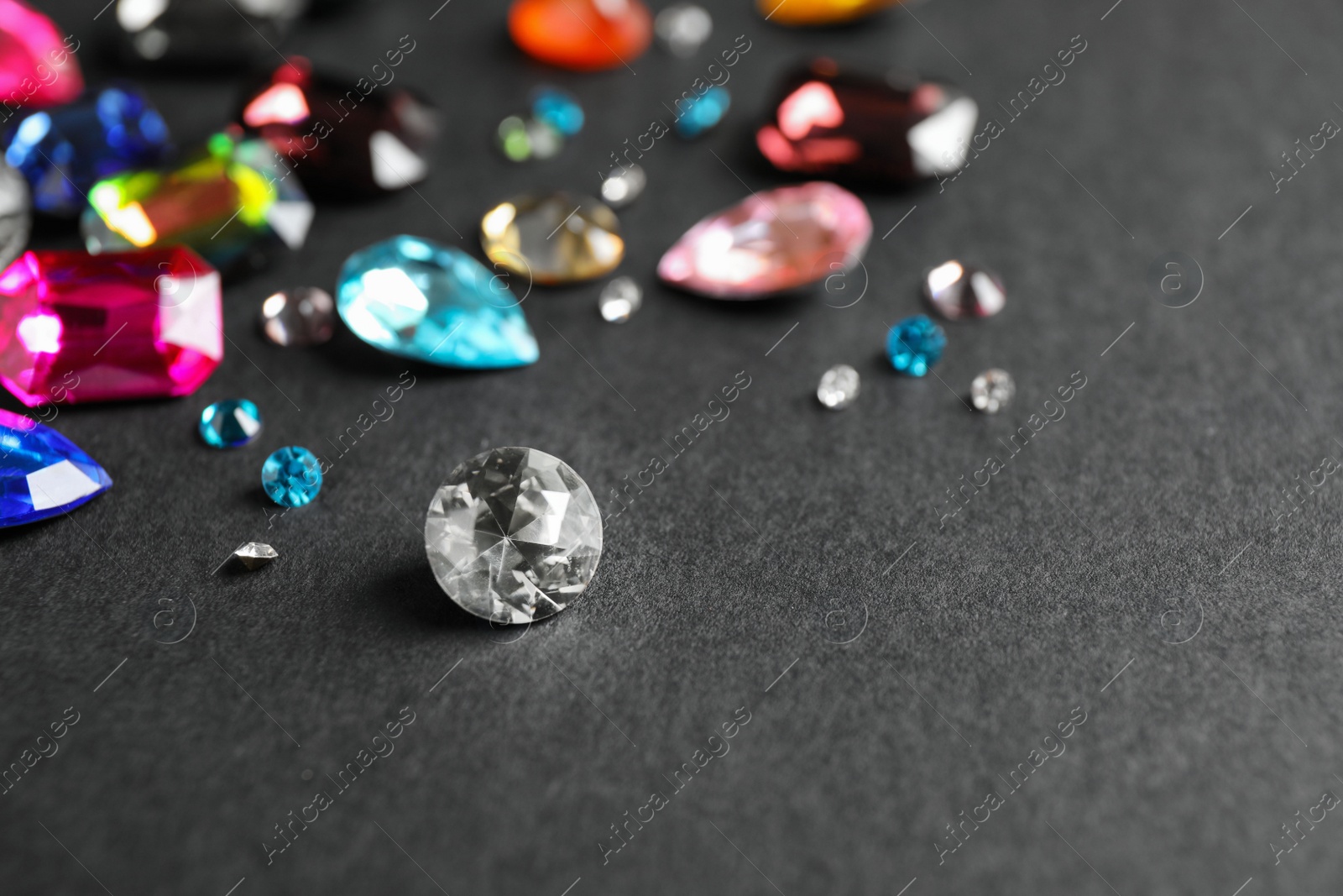 Photo of Different beautiful gemstones on black background. Space for text