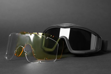 Tactical glasses and different lenses on black background, closeup. Military training equipment