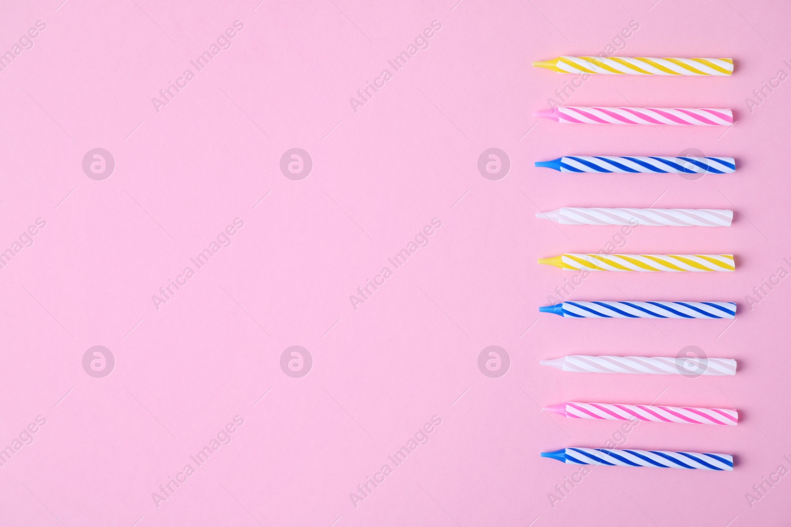 Photo of Colorful striped birthday candles on pink background, flat lay. Space for text