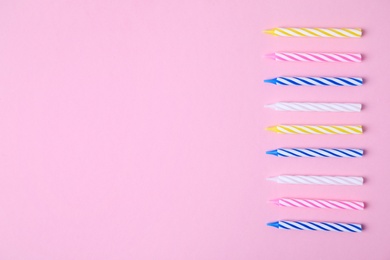 Photo of Colorful striped birthday candles on pink background, flat lay. Space for text